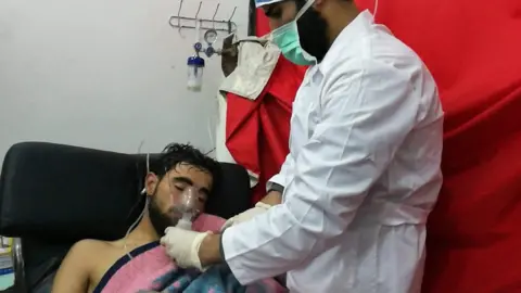 Anadolu Agency A man is treated by a medic after an attack allegedly involving chlorine in Saraqeb, Syria, on 4 February 2018