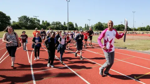 Getty Images Baton bearer Colin Jackson CBE holds the Queen's Baton during the Birmingham 2022 Queen's Baton Relay on a visit to Basildon Sporting Village