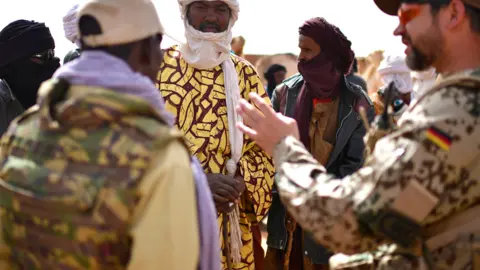 Getty Images Farmers talk to German UN soldiers during a weekly cattle market on the outskirts of Gao, Mali - 2017