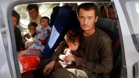 EPA An Afghan family, who have escaped from the volatile city of Ghazni province, poses for a photograph in the entrance gate of Kabul, Afghanistan, 13 August 2018.