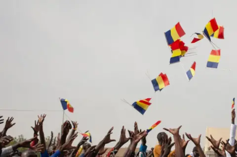 AFP People throw Chad's national flag in the air in celebration.