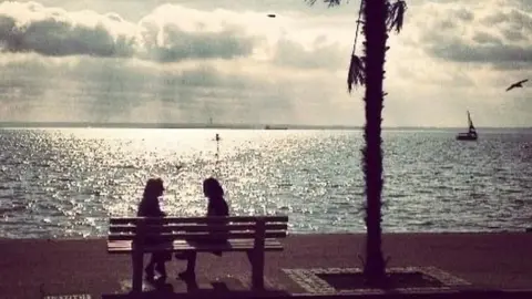 Janet Janet sitting on a bench by the sea