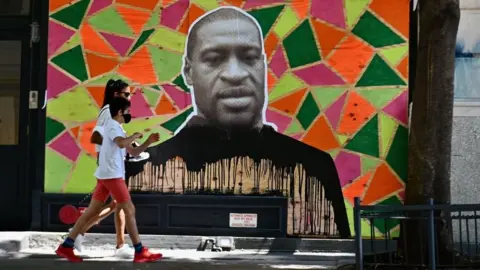 Getty Images People walk past a mural to George Floyd in New York, June 2020
