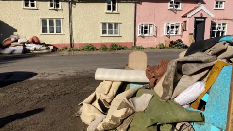 Jenny Kirk/BBC Carpets, furniture and other items piled in the street