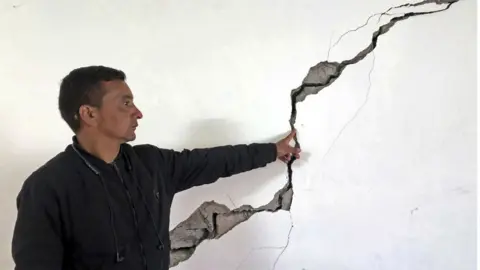 Getty Images A resident shows a crack on the wall of his house at Joshimath in Chamoli district of India's Uttarakhand state on January 8, 2023.