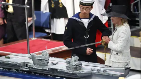 MOD AB Callum Hui and Dr Karen Kyd cutting the cake at the commissioning of HMS Queen Elizabeth.