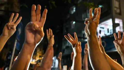 Getty Images People give a three-finger salute