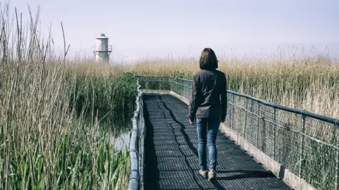 Getty Images A woman walking towards West Usk Lighthouse on the Gwent Levels