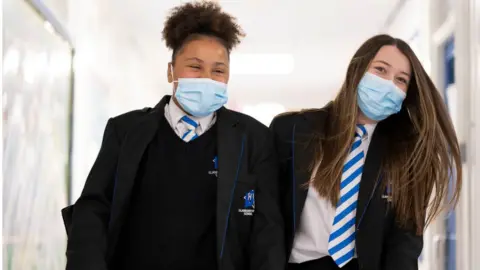 Getty Images Two girls wearing face masks walk down the corridor of Llanishen High School