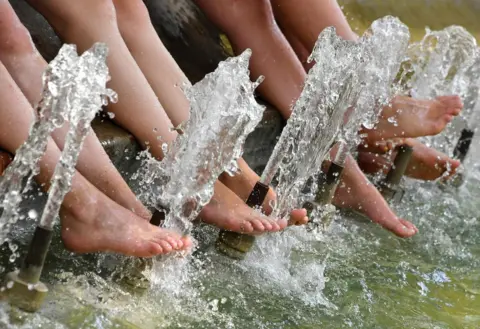 AFP Tourists refresh their feet in a pool during a heatwave in Montpellier