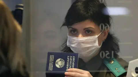 Getty Images A woman in a face mask produces her passport at Minsk National Airport amid the COVID-19 pandemic