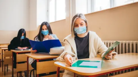 Getty Images Three students in marks sit at tables