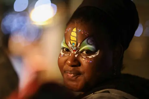 Reuters A woman wearing face paint smiles.