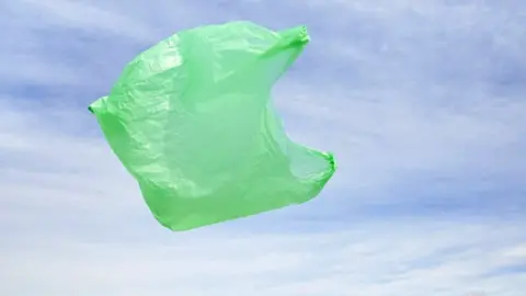 Getty Images Green plastic bag floating in front of blue sky