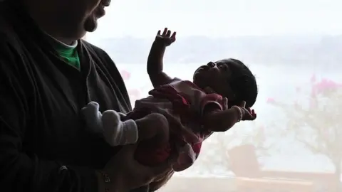 AFP/Getty Images In this 19 February 2010 photograph, US citizen Brad Fister, 29, cradles his 23-day old daughter Ashton in Hyderabad.