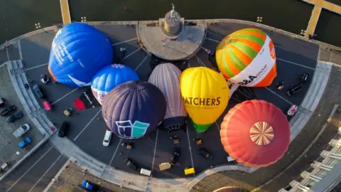 PA Media Hot air balloons inflate and tether from Bristol Harbourside