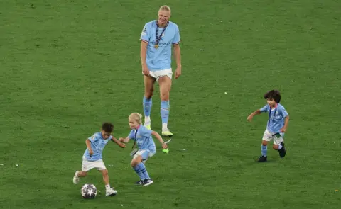 Reuters Manchester City's Erling Braut Haaland on the pitch with kids after winning the Champions League