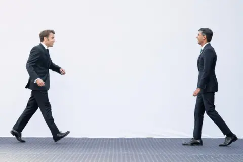 Stefan Rousseau/PA Images French President Emmanuel Macron strides towards Prime Minister Rishi Sunak ahead of their meeting