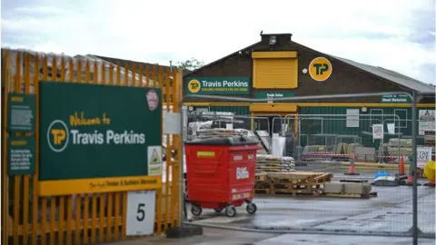 A Travis Perkins outlet showing piles of wood in a yard