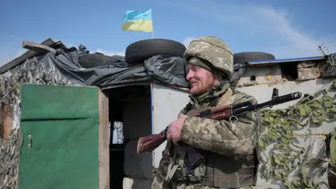 Getty Images A Ukrainian soldier patrols at the checkpoint in the village of Shyrokyne near Mariupol. Photo: 26 April 2021