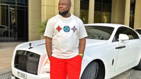 Hushpuppi/Instagram Hushpuppi in front of a car