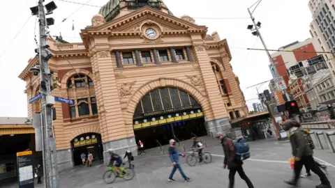 EPA People pass Flinders Street Station in Melbourne during lockdown
