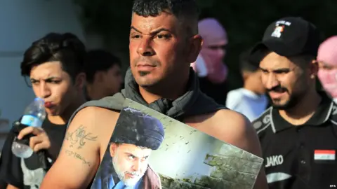 EPA An Iraqi protester carries a poster of Shia leader Moqtadr al-Sadr