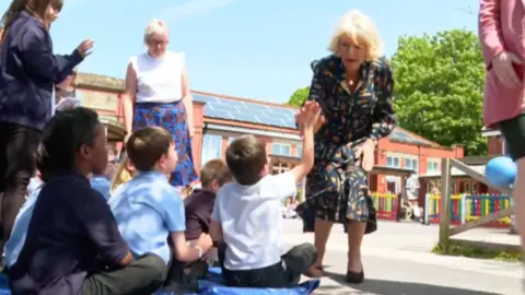 Queen Camilla high fiving a boy at Shirehampton Primary School