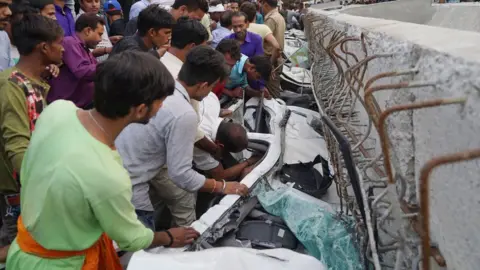 AFP Indian bystanders gather at the site of a flyover collapse in Varanasi on May 15, 2018.