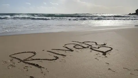 The name Rivah written in the sand on a beach.