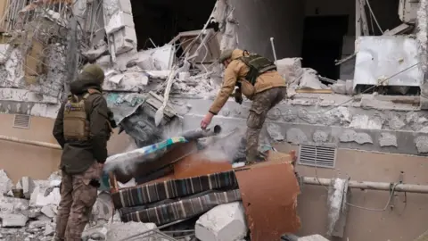 Reuters Ukrainian service men remove a grad rocket in a damaged house in Kherson