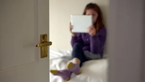 girl in bedroom on tablet