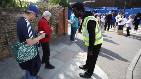 Reuters Fans show their Covid status to stewards outside the Women's Super League game between Chelsea and Everton on Sunday