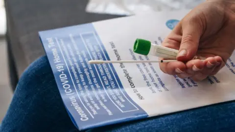 Getty Images Person holds a Covid testing kit on their lap