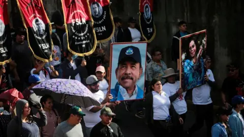 Getty Images Supporters of Nicaraguan President Daniel Ortega and Vice-President Rosario Murillo take part in a pro-government march in Managua on February 11, 2023. -