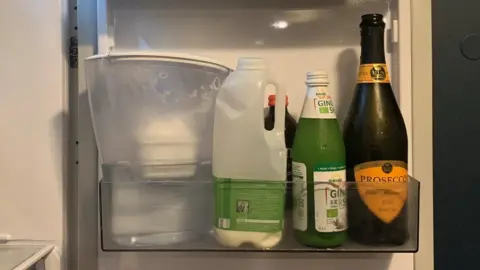 Jess Warren/BBC A fridge door with an open bottle of prosecco