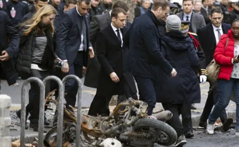 EPA French President Emmanuel Macron (centre) assesses damage following the "Yellow Vests" protest a day earlier, next to the Champs Elysee in Paris, France, 2 December 2018