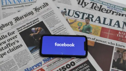 EPA A phone showing the Facebook logo on a spread of Australian newspapers