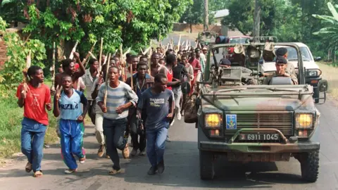 AFP French soldiers on patrol pass ethnic Hutu troops from the Rwandan government forces 27 June 1994, near Gisenyie, about 10kms from the border with Zaire.