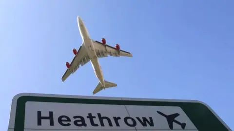 Reuters Plane flying over Heathrow sign