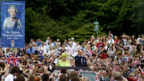 PA Media The Queen and Prince Phillip waving from a car amidst crowds