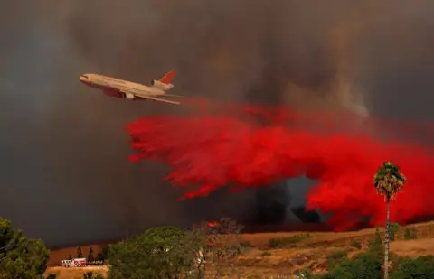 Reuters A DC-10 aircraft drops fire retardant on a wildfire in Orange, California, 9 October