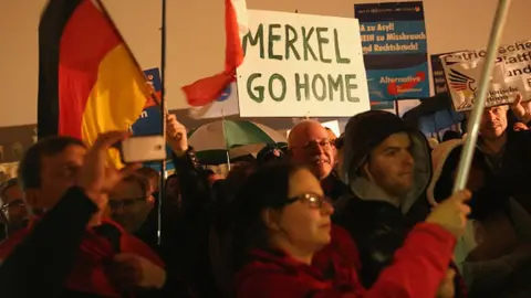 Getty Images Supporters of the AfD political party protest against German Chancellor Angela Merkel's liberal policy towards taking in migrants and refugees