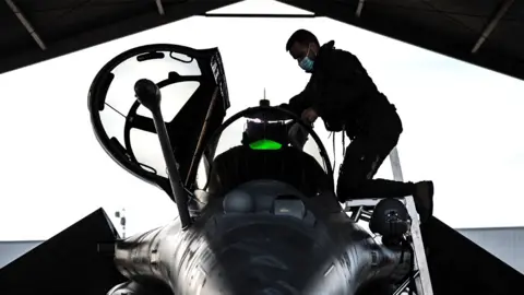 Getty Images A French fighter jet pilot inspects his aircraft prior to taking off for a daily Nato border watch mission over Poland