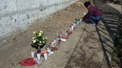AFP via Getty Images Local residents have laid flowers, candles and bottles of water at the scene of the crash