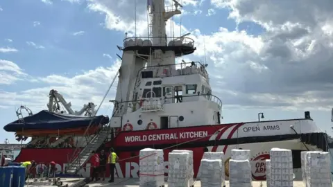 WORLD CENTRAL KITCHEN/OPEN ARMS Picture of a ship with pallets of food in front of it