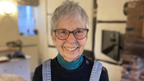 Val Compton smiling in her living room