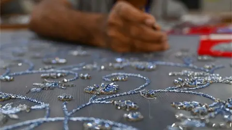 Getty Images In this picture taken on January 7, 2023, an embroider of Shanagar, a luxury Mumbai-based hand-embroidery atelier, works on a design at their production facility in Mumbai. -