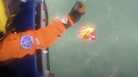 HM Coastguard Swimmer being pulled out of the water through a helicopter rescue