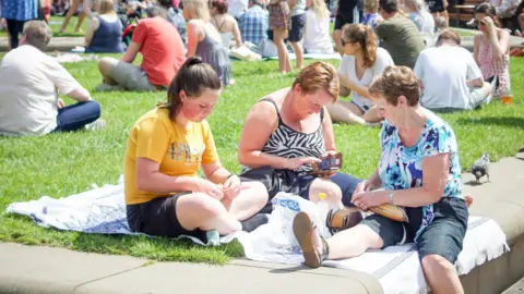 Getty Images Three women have a picnic in the sun